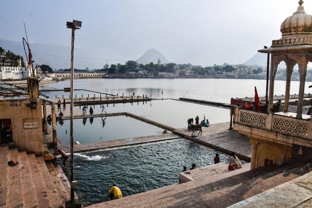 Tranquil view of Pushkar Lake with people and ghats in Rajasthan, India.