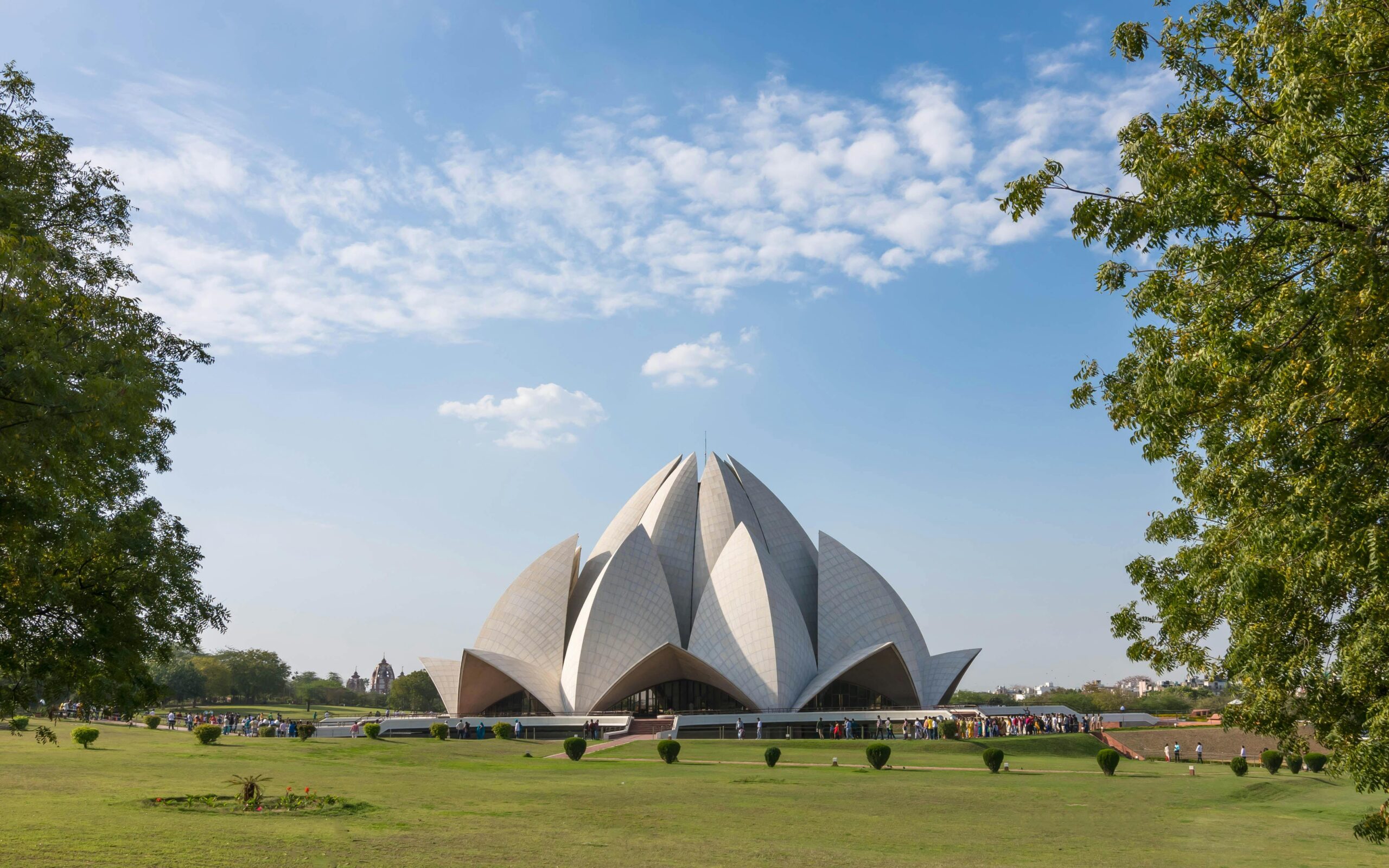 A stunning view of the Lotus Temple in Delhi, surrounded by greenery and clear skies.